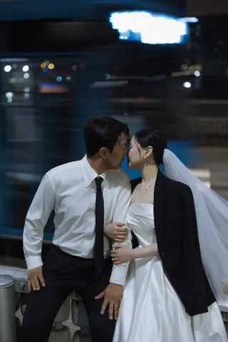 밤거리에서 나란히 앉아 입맞춤하는 신랑과 신부
