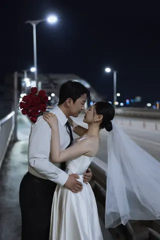 붉은 장미와 베일을 두르고 서로 마주 보는 신랑과 신부