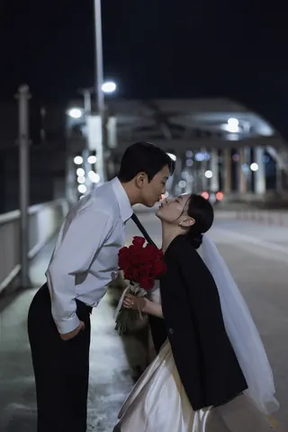 붉은 장미 꽃다발을 사이에 두고 입맞춤하는 신랑과 신부