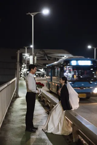 밤거리 버스 옆에서 서로 마주 보고 웃는 신랑과 신부