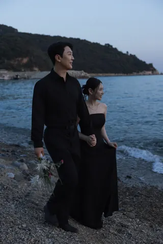 바닷가에서 손을 잡고 나란히 서 있는 신랑과 신부