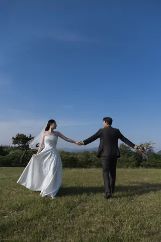 초원에서 서로 손을 잡고 걷는 신랑과 신부