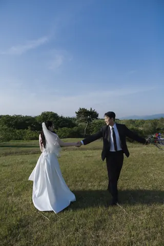 초원에서 손을 잡고 환하게 웃는 신랑과 신부