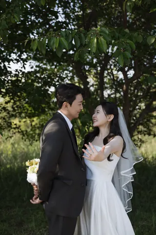 숲에서 서로 바라보며 결혼반지를 보여 주는 신랑과 신부