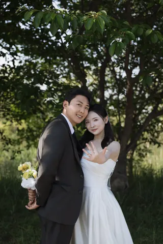 나무 아래에서 결혼반지를 보여 주며 함께 웃는 신랑 조황덕과 신부 홍은주